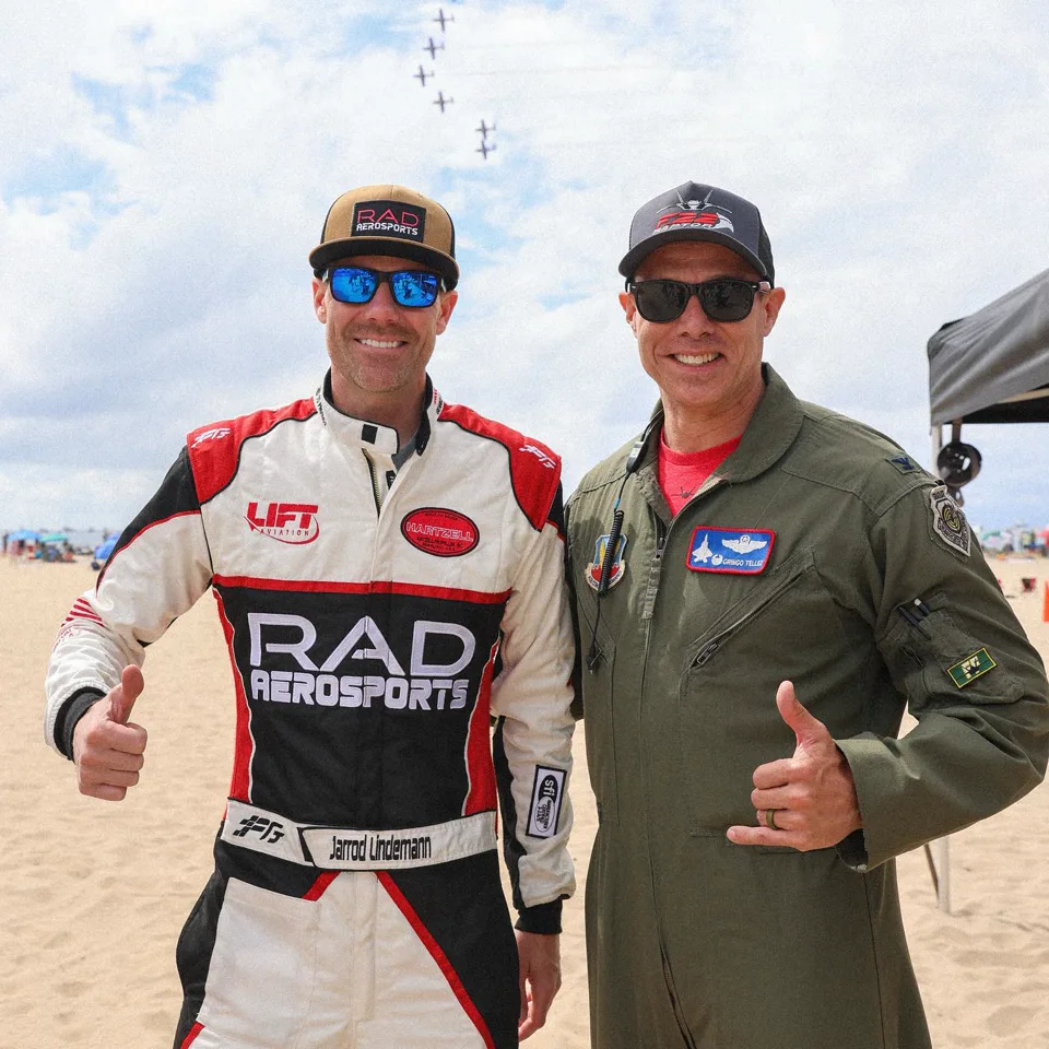 Jarrod Lindemann in his red and white RAD Aerosports FervoGear suit, giving a thumbs up beside a pilot Jarrod Lindemann in his red and white RAD Aerosports FervoGear suit, giving a thumbs up beside a pilot